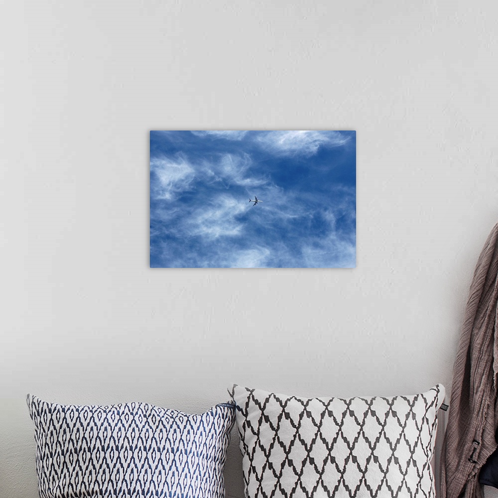 A bohemian room featuring Plane in cloud filled blue sky.