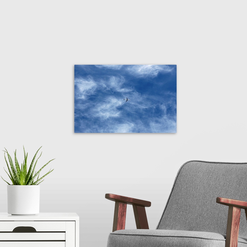 A modern room featuring Plane in cloud filled blue sky.