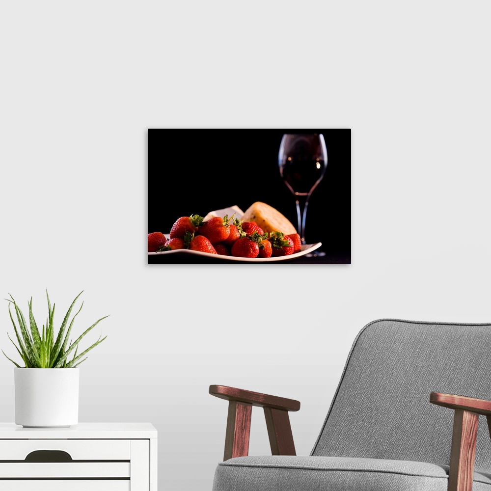 A modern room featuring This is a horizontal photograph of fruit, cheeses, and wine against a dark backdrop making this a...
