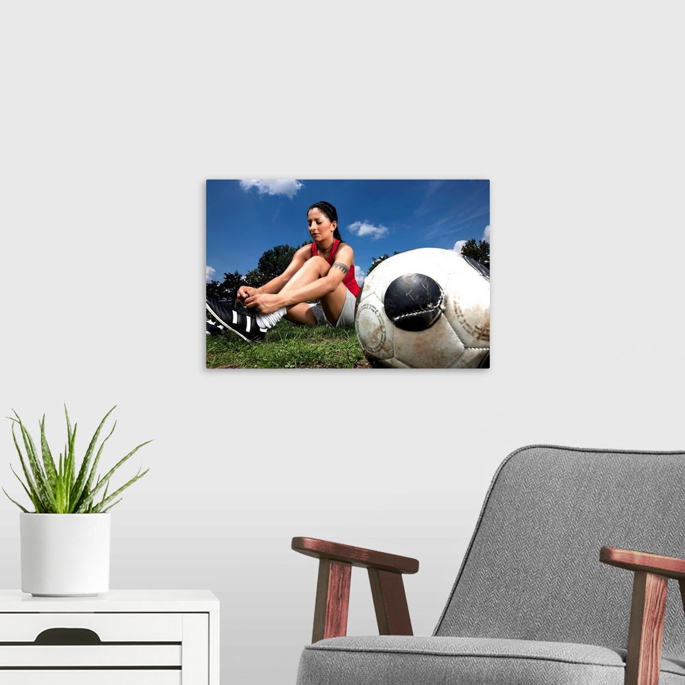 A modern room featuring Portrait of female football player tying her shoes