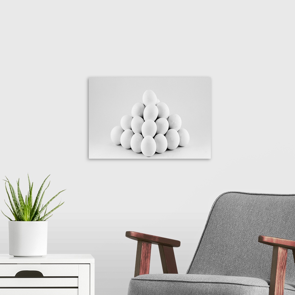 A modern room featuring Pyramid of white eggs on bright gray background.