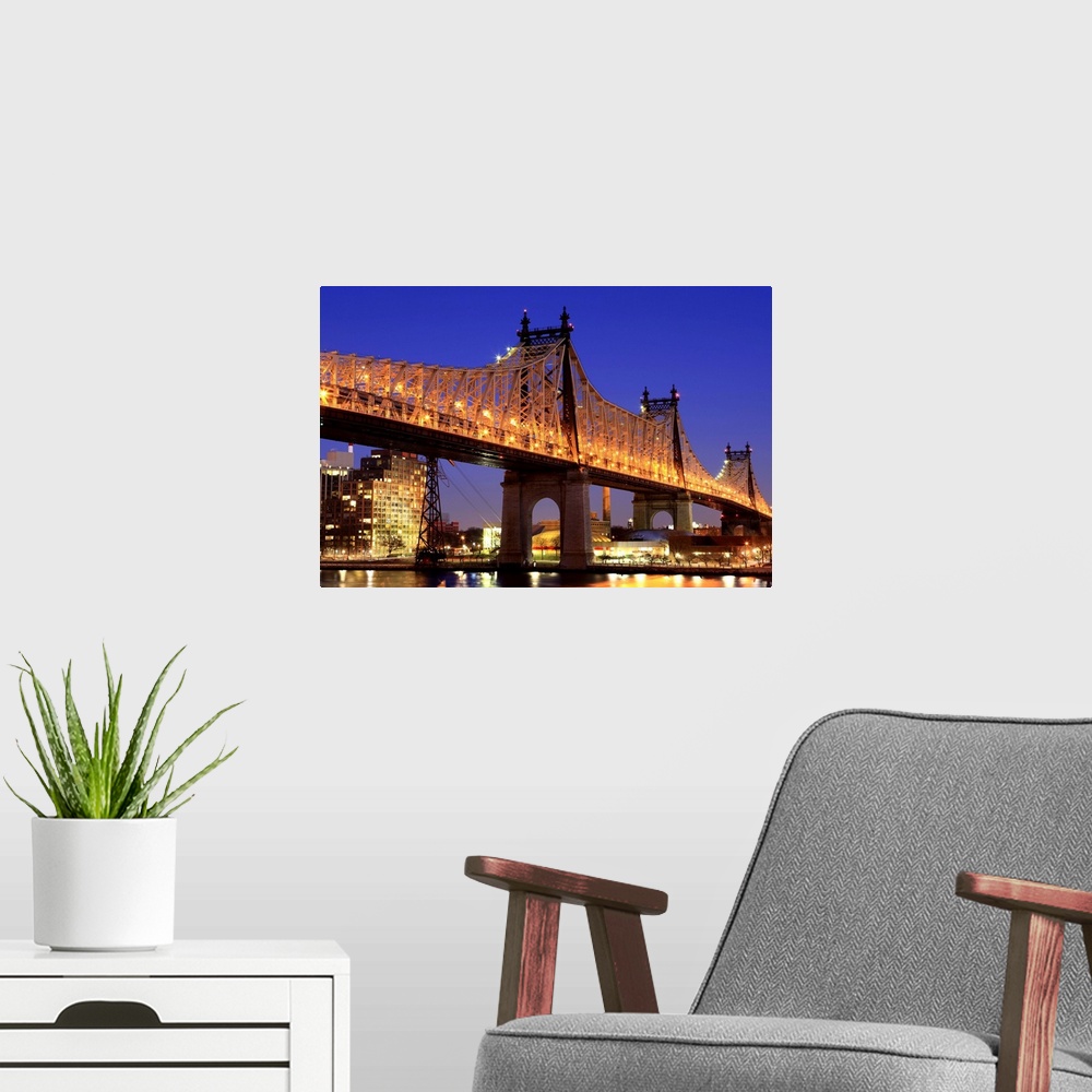 A modern room featuring Queensboro Bridge and the East River at night, New York.  Looking towards Roosevelt Island.