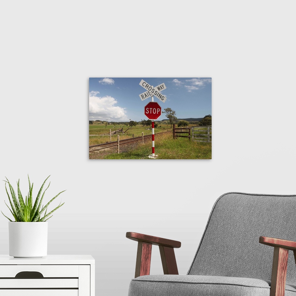 A modern room featuring A railway crossing and stop sign in farmland west of Auckland on a summer afternoon.