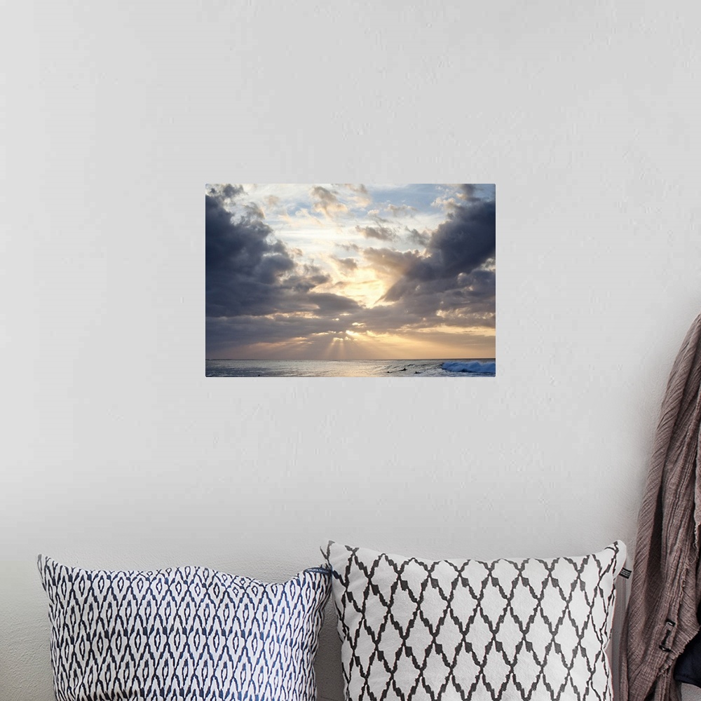 A bohemian room featuring Crepuscular rays of light break through the sky over the blue ocean, surfers in the background