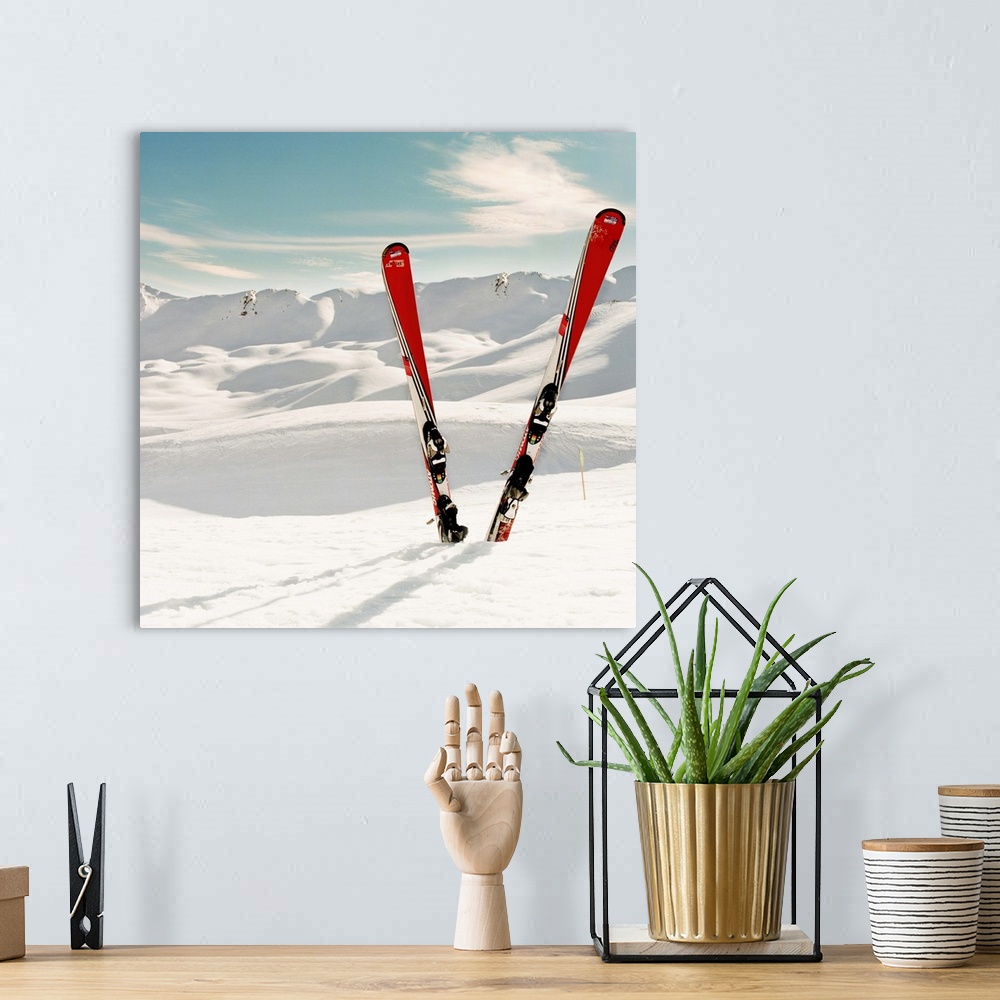 A bohemian room featuring Red pair of ski standing in snow.Mountains in background