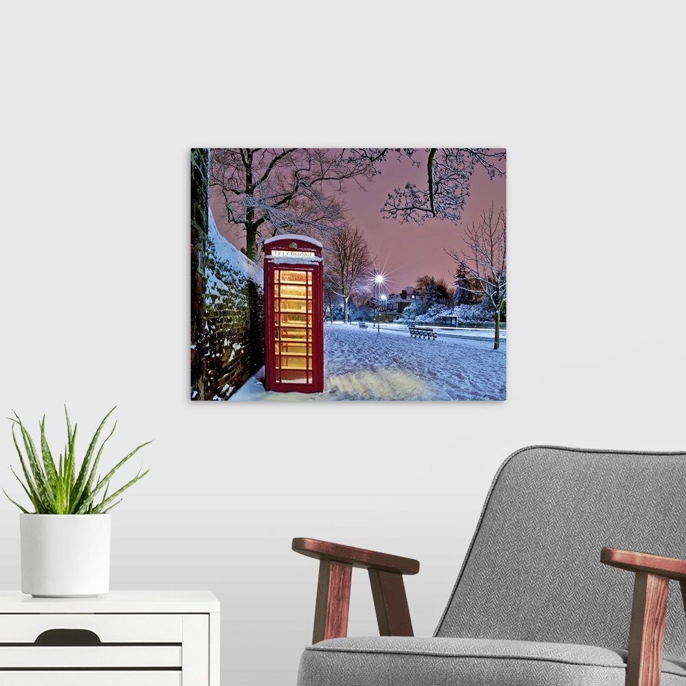 A modern room featuring Red phone box covered in snow in Hampstead, North London.
