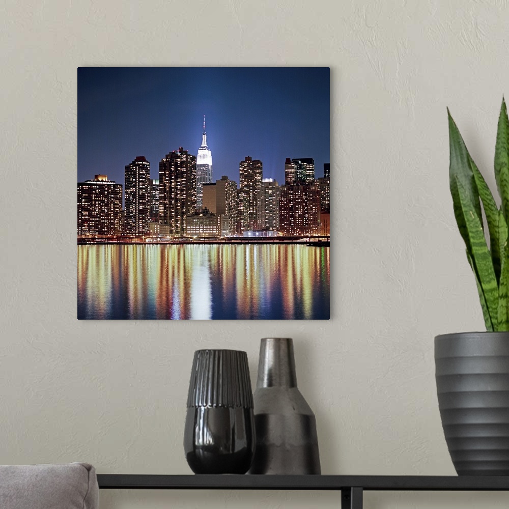 A modern room featuring Photograph of "The Big Apple's" skyline and waterfront at dusk.  The buildings are lit up and lig...