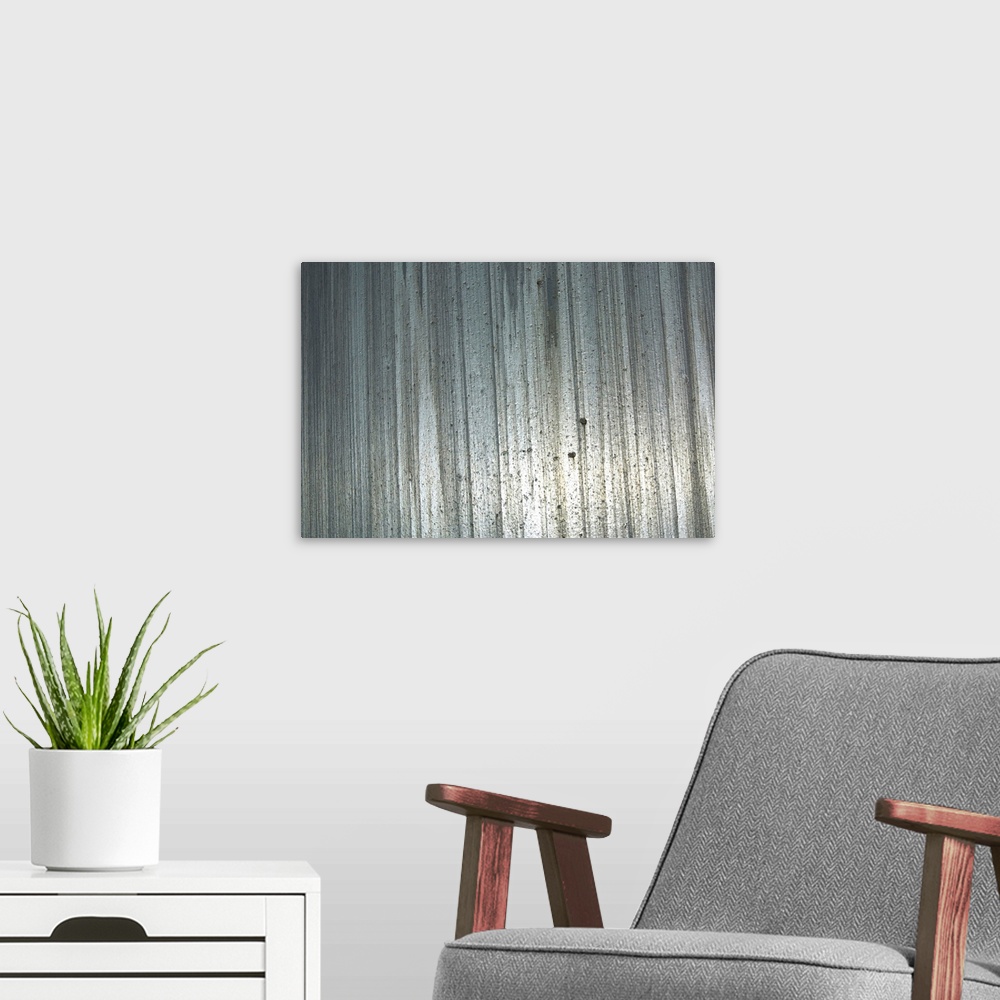 A modern room featuring Big, horizontal photograph of a shiny metal surface with vertical streaks and a rough, pitted tex...