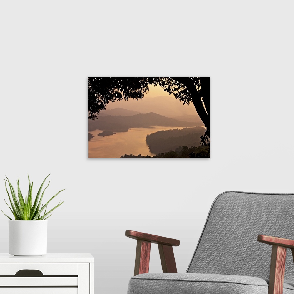 A modern room featuring View of river Sharavathi with mountain in background and silhouette tree in foreground at mist ev...