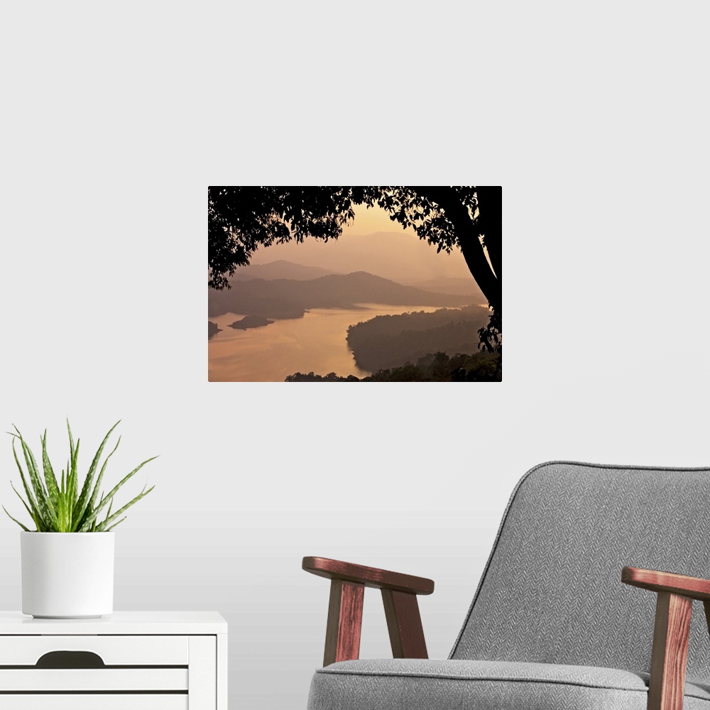 A modern room featuring View of river Sharavathi with mountain in background and silhouette tree in foreground at mist ev...