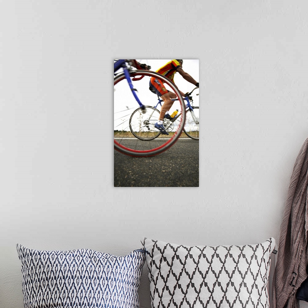A bohemian room featuring Cyclist speed by and a picture is snapped of the front tire of the cyclist closest and the person...