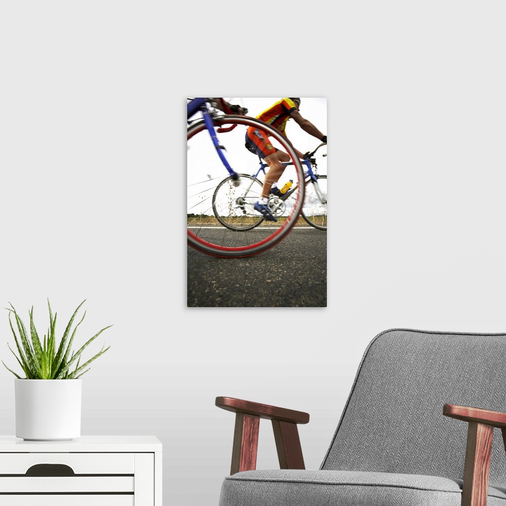 A modern room featuring Cyclist speed by and a picture is snapped of the front tire of the cyclist closest and the person...