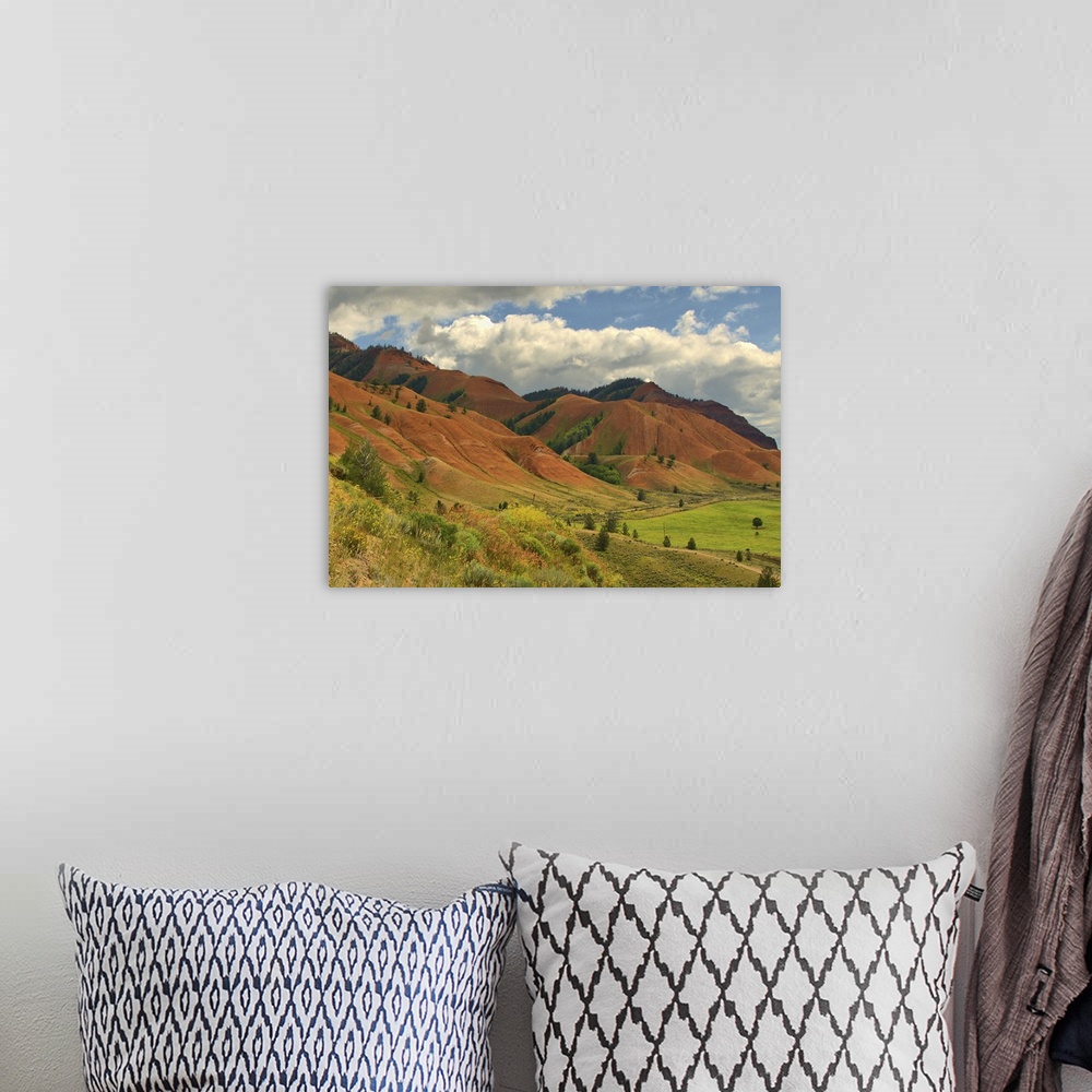A bohemian room featuring Rolling red hills under a cloudy blue sky during the summer in rural Wyoming