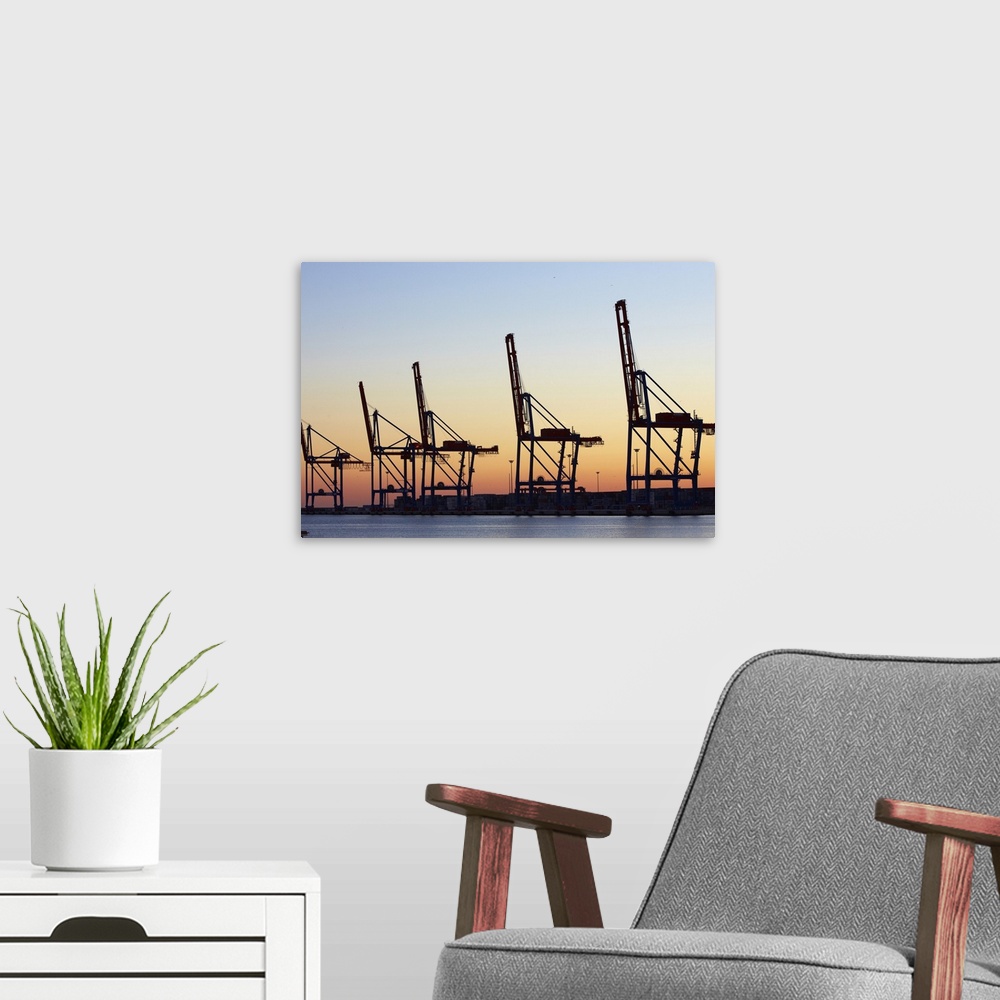 A modern room featuring Row of cranes in the dock area of Malaga at sunset