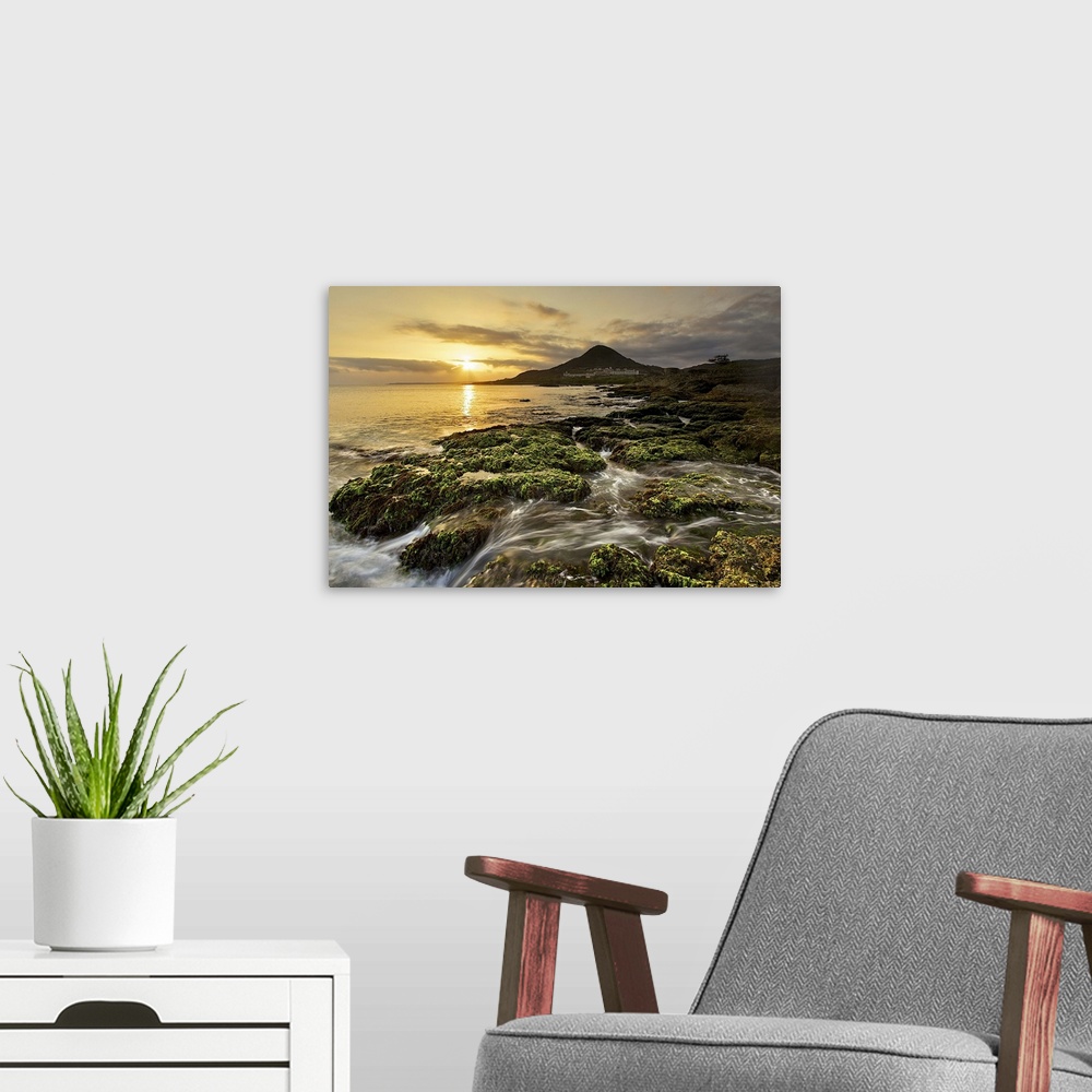 A modern room featuring View of sailboat rock at dusk with golden sun and waves flowing down green mossy coral reefs.