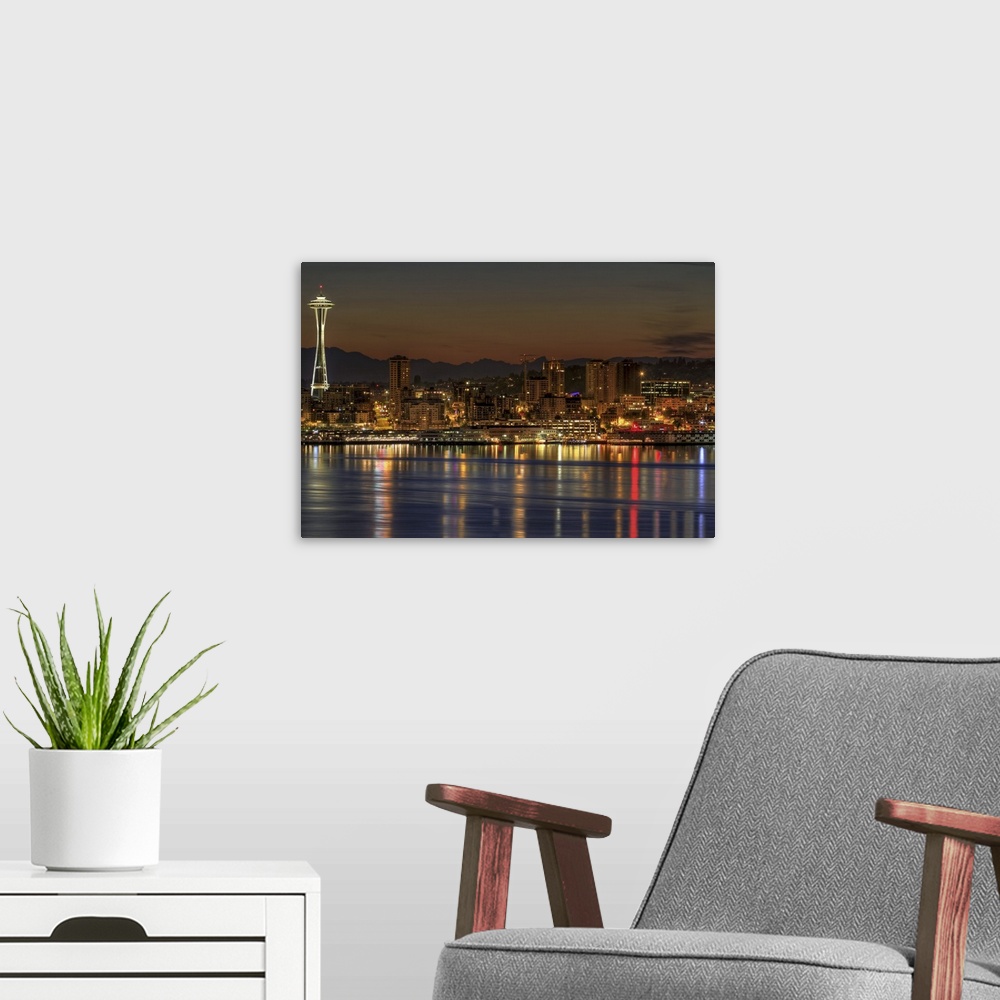 A modern room featuring Oversized, landscape photograph of a lit Seattle skyline, including the Space Needle, during earl...