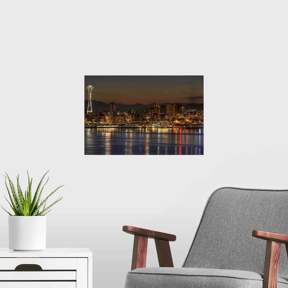 A modern room featuring Oversized, landscape photograph of a lit Seattle skyline, including the Space Needle, during earl...