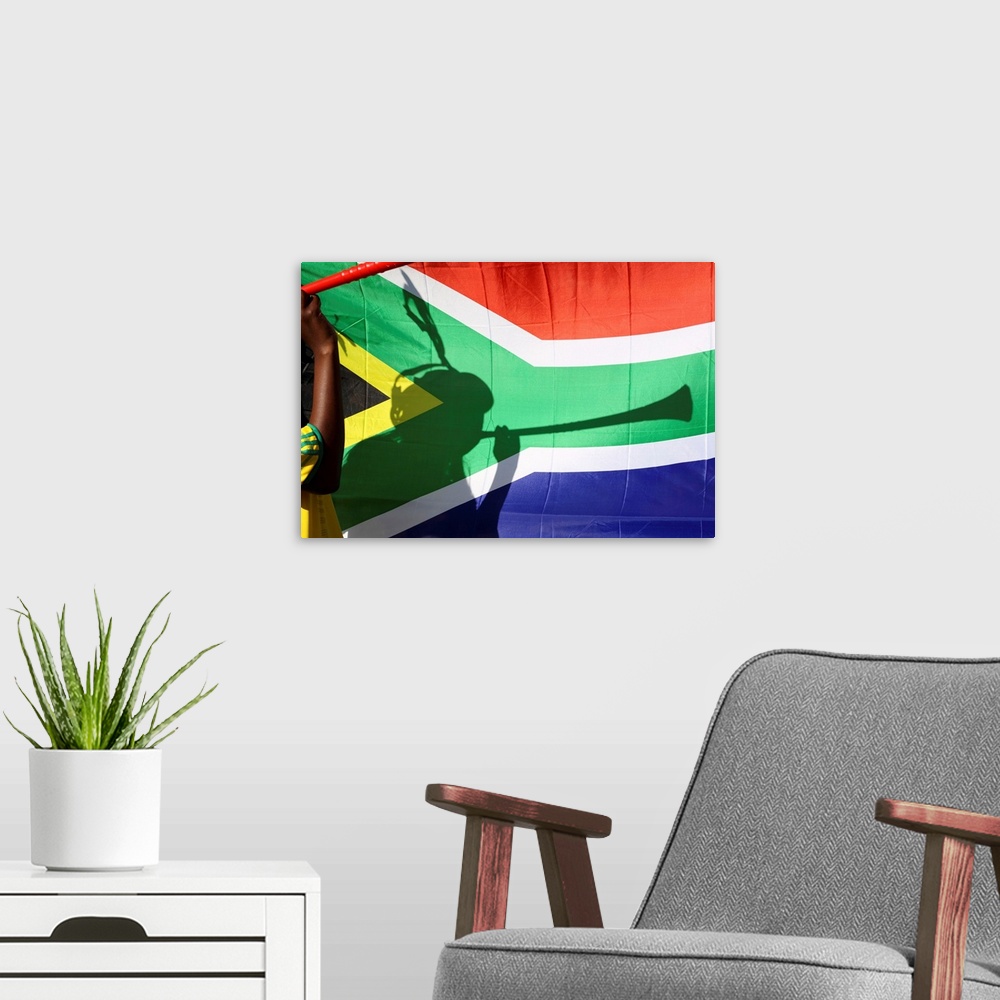 A modern room featuring Shadow of soccer supporter blowing vuvuzela, South African flag in background, Johannesburg, Sout...