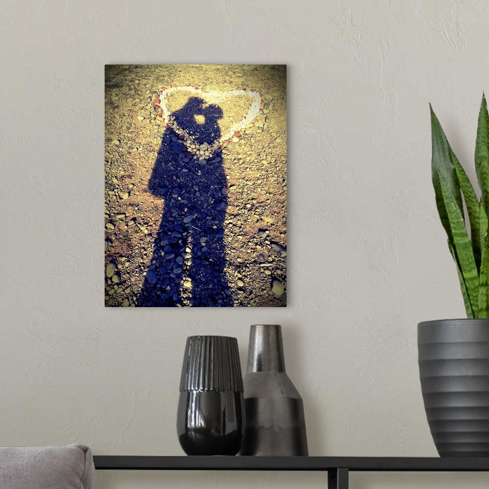 A modern room featuring Shadows of couple kissing over heart of stones.