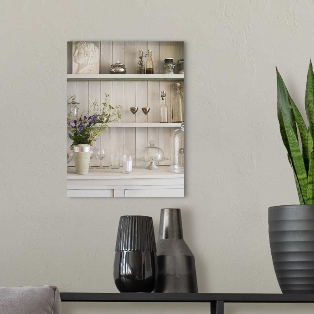 A modern room featuring Shelf with flowers and vintage glassware