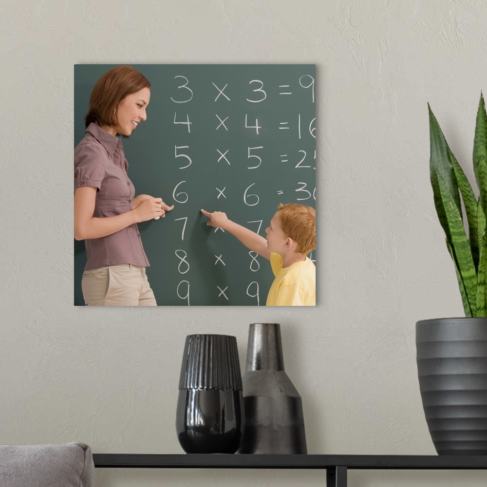 A modern room featuring Side profile of a female teacher teaching her student on a blackboard