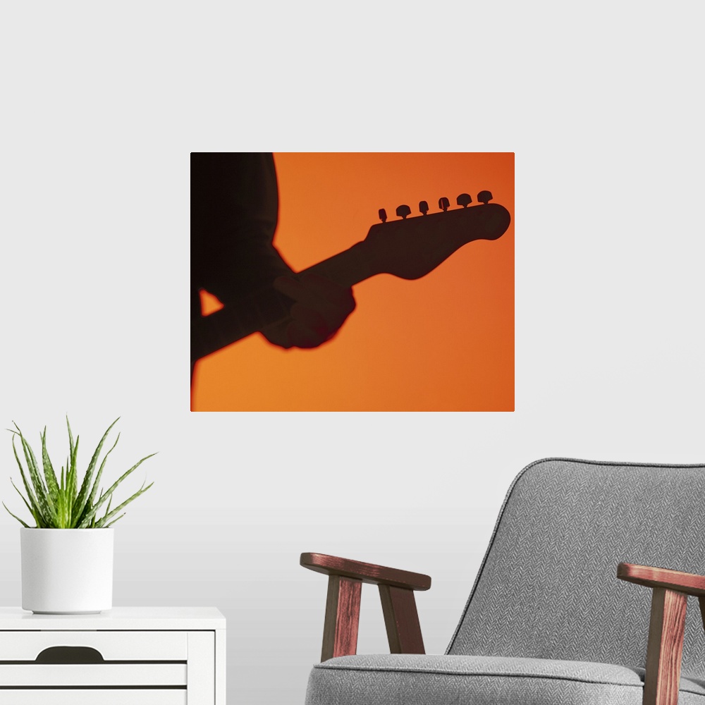 A modern room featuring silhouette of a person playing a electric guitar