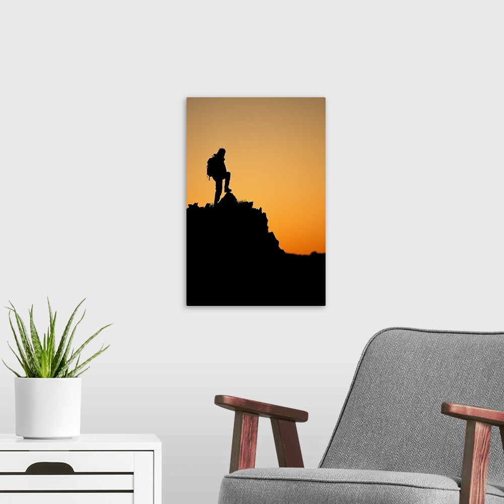 A modern room featuring Silhouette of hiker standing on peak at sunset