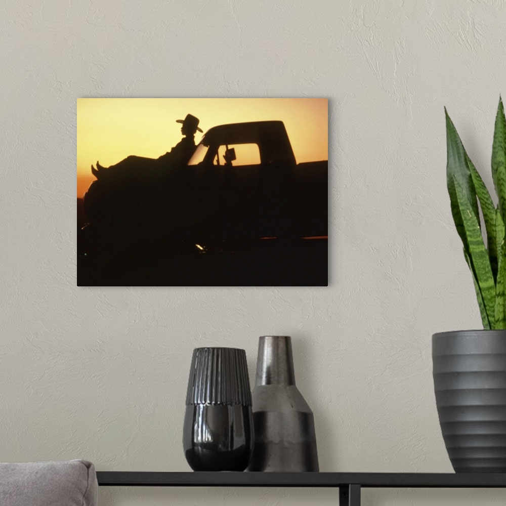 A modern room featuring Silhouette of man reclining on hood of truck
