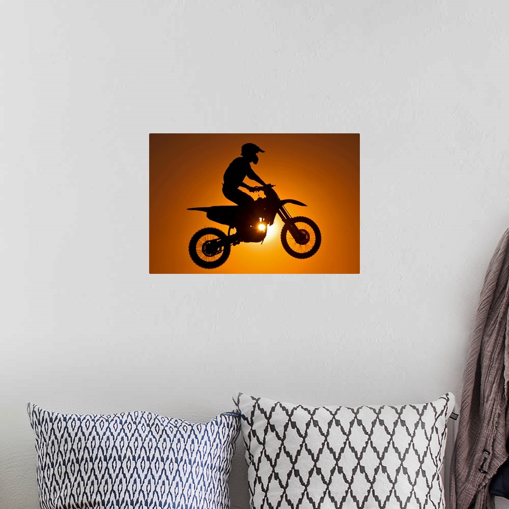 A bohemian room featuring Silhouette of motocross race in mid air at sunset.