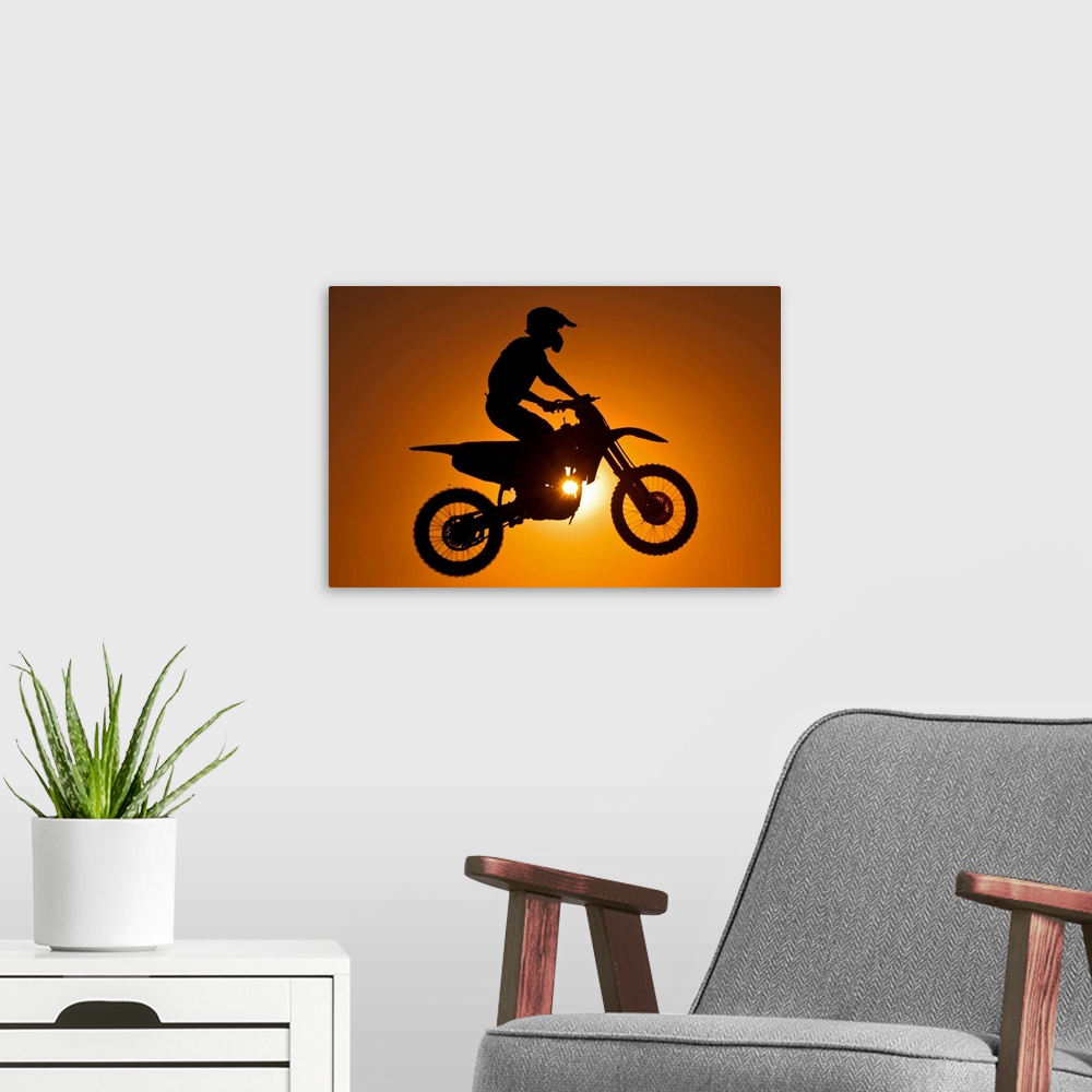 A modern room featuring Silhouette of motocross race in mid air at sunset.