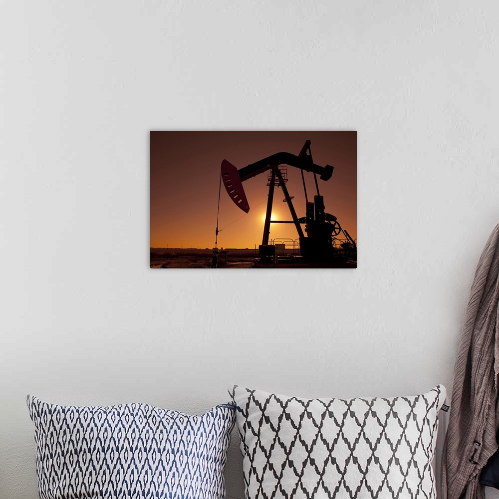 A bohemian room featuring Silhouette of an oil pump jack on rig as the sun sets in the background.