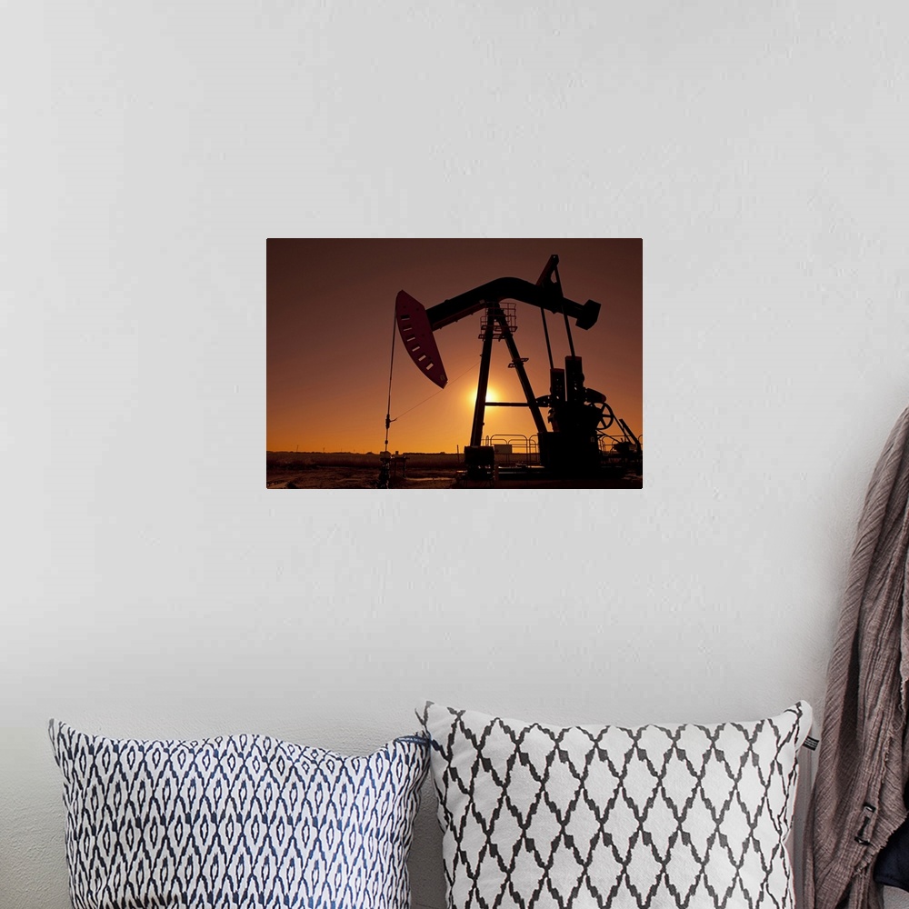 A bohemian room featuring Silhouette of an oil pump jack on rig as the sun sets in the background.