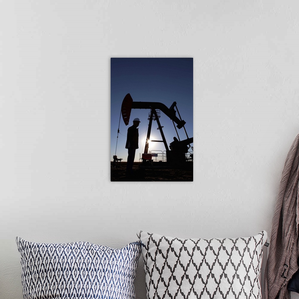 A bohemian room featuring Silhouette of oil worker by pump jack on rig
