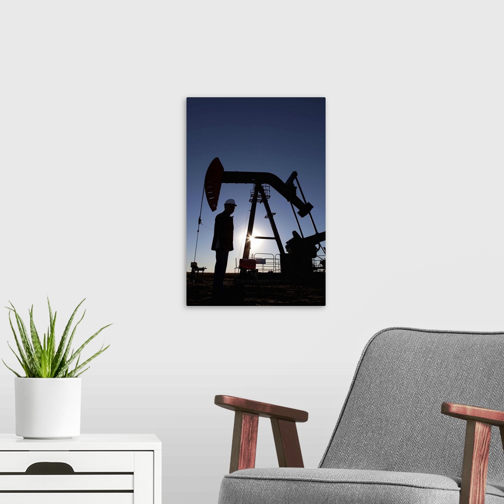 A modern room featuring Silhouette of oil worker by pump jack on rig