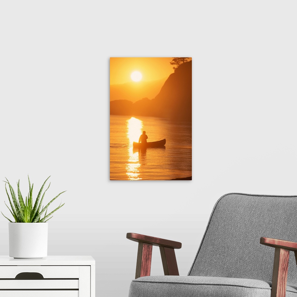 A modern room featuring Silhouette of person canoeing at sunset
