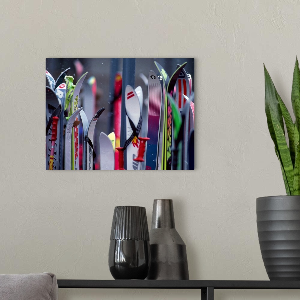A modern room featuring Big, landscape photograph of the tops of many colorful ski boards on a slightly out of focus back...