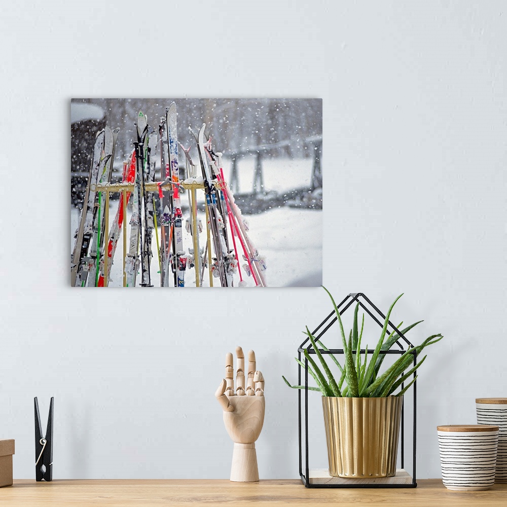 A bohemian room featuring In this photograph multiple skis are stored on an outside rack as large white snowflakes fall all...