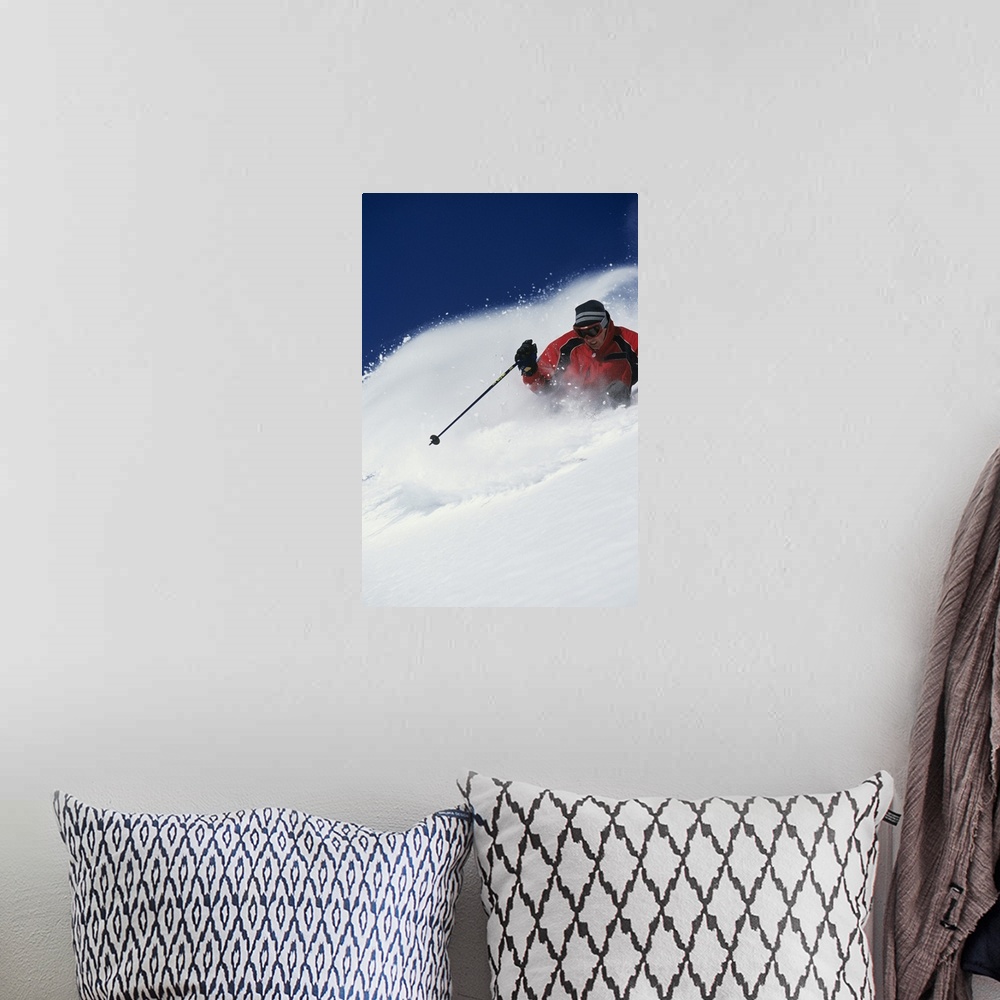 A bohemian room featuring A big vertical piece of a skier coming down a mountain with snow flying up as he skis side to side.