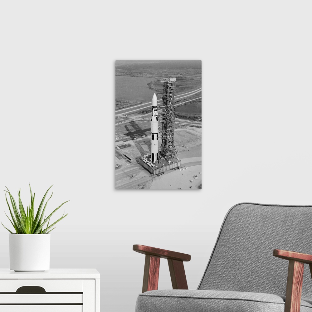 A modern room featuring Cape Kennedy: The Skylab orbital workshop, atop a Saturn V rocket, crawls to its launching pad ea...