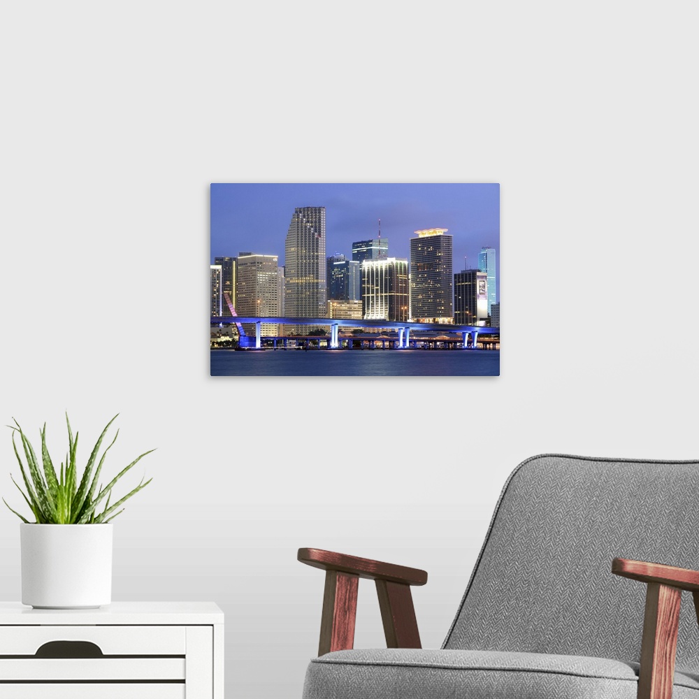 A modern room featuring Large canvas photo art of the Miami cityscape lit up at night along the waterfront.