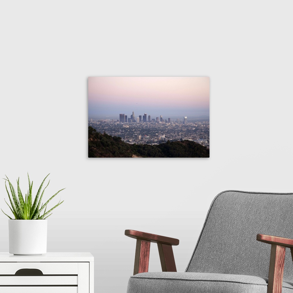 A modern room featuring Landscape view of skyscrapers of downtown LA with hills of Griffith Park in foreground as seen at...