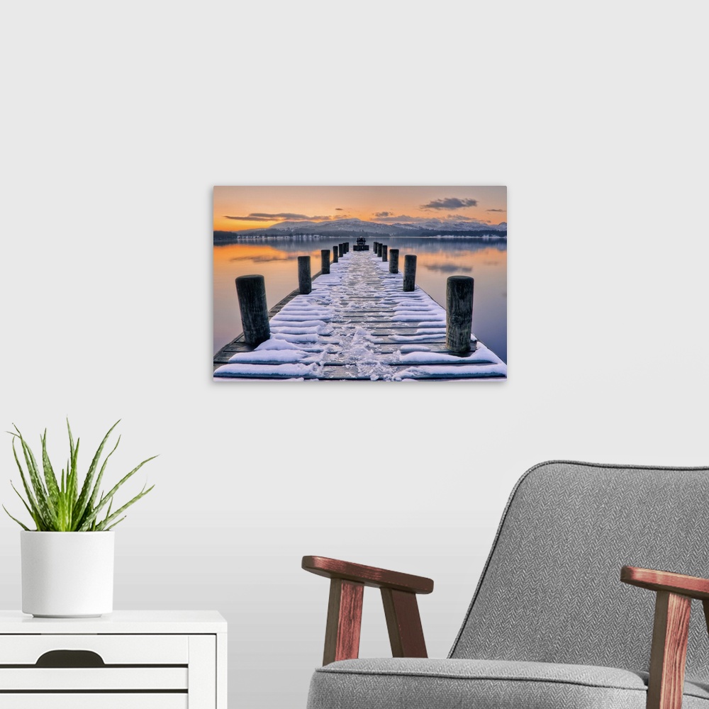 A modern room featuring Snow covered jetty leading to beautiful sunset scene.