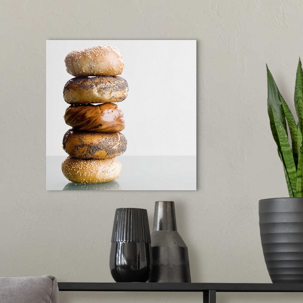 A modern room featuring Different types of bagels are stacked high and photographed on a glass surface.