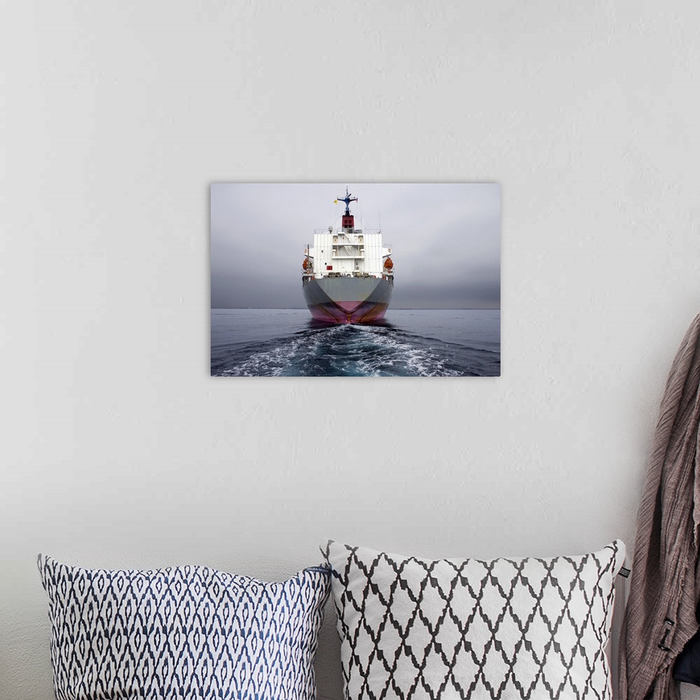 A bohemian room featuring Stern of a grey and pink cargo ship.