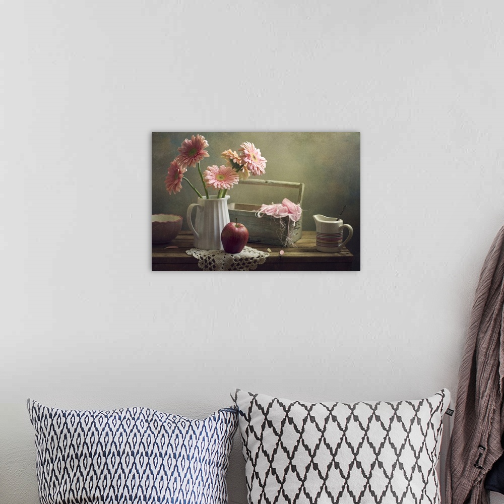 A bohemian room featuring Still life with pink gerberas and red apple on table.