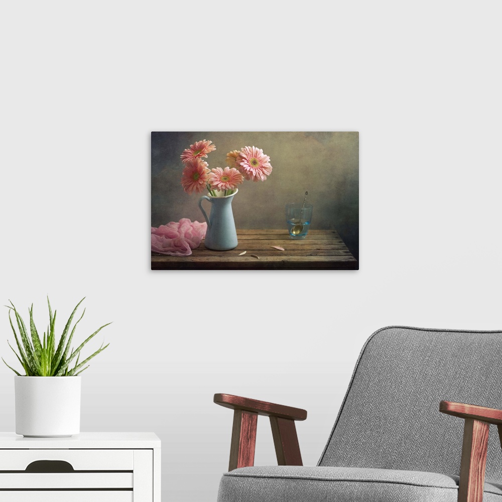 A modern room featuring Still life with pink gerberas flowers in blue pitcher jug anf glass of water.