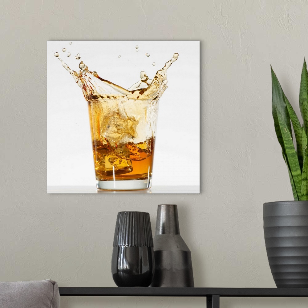 A modern room featuring Studio shot of ice cubes splashing into glass of whiskey