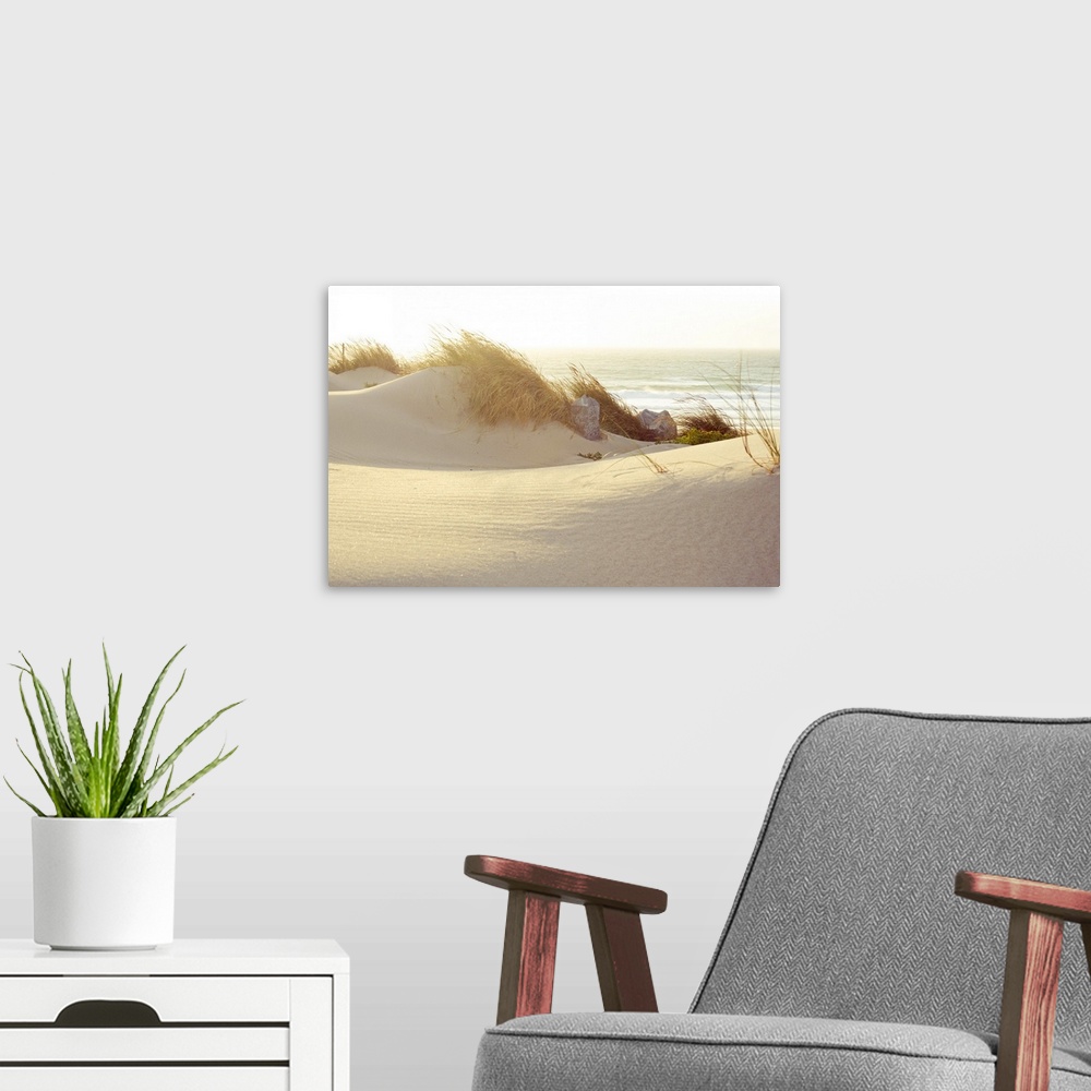 A modern room featuring Landscape photograph of grassy dunes beneath a setting sun, on a beach in Lisbon, Portugal, the w...