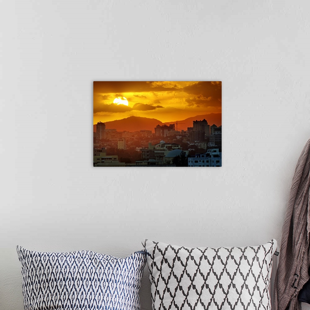 A bohemian room featuring Sunset, Santo Domingo, Domenican Republic, large sun, cloudy sky, orange mood, mountains in backg...