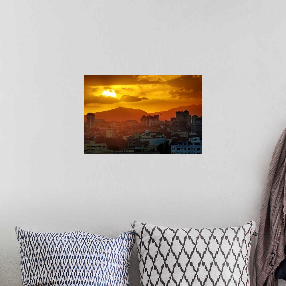 A bohemian room featuring Sunset, Santo Domingo, Domenican Republic, large sun, cloudy sky, orange mood, mountains in backg...